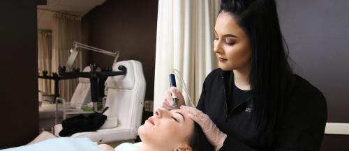 One female Esthetician student applies a skin treatment to another student in the ˾ salon spa.