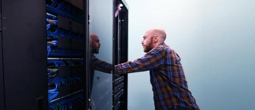 Male computer technician reviews a ˾ computer server.